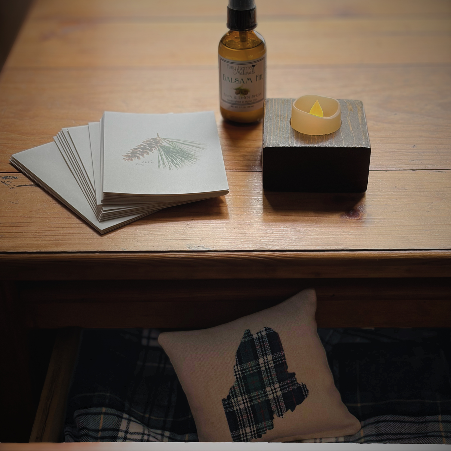 Handmade Maine sachet made with upcycled flannel, displayed with balsam fir spray, pine notecards, and candlelight in the Flannel, Fir & Firelight collection.