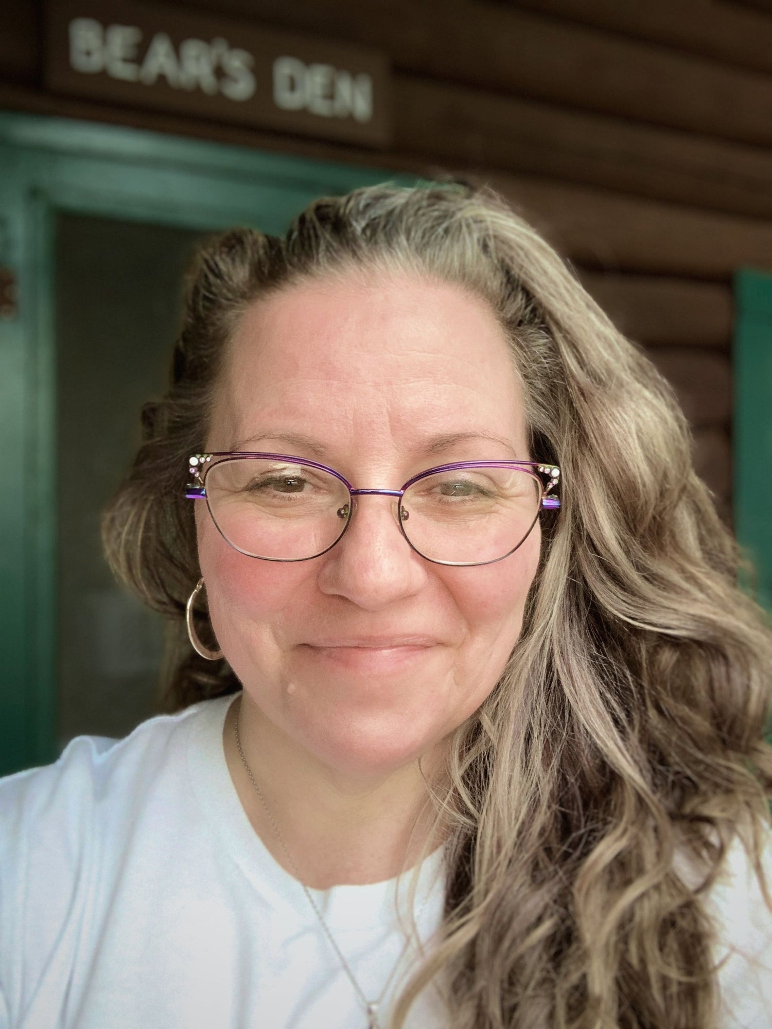 Kim Napolitano, founder of Perry Home Naturals, smiling outside a cabin at Kidney Pond in Baxter State Park, Maine.